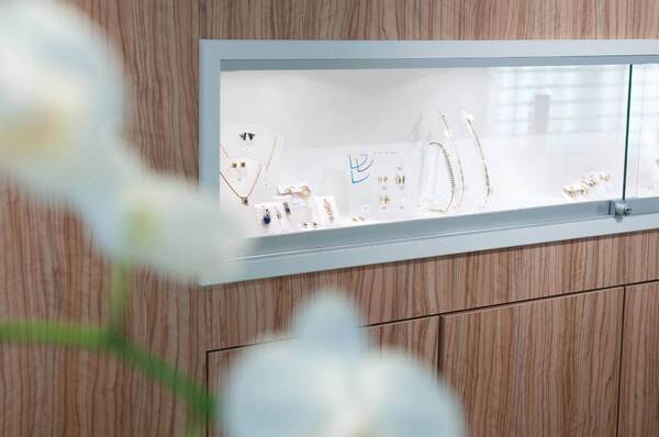 Schmuckauslage mit goldenen Ketten, Ringen und Ohrringen in einer Glasvitrine im Juweliergeschäft.