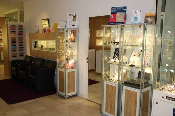 Modernes Juweliergeschäft mit beleuchteten Vitrinen voller Schmuck und Sitzbereich.