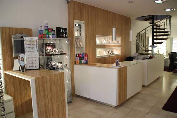 Modernes Optiker- und Juweliergeschäft mit Glasvitrinen, Brillen, Uhren und Schmuck.